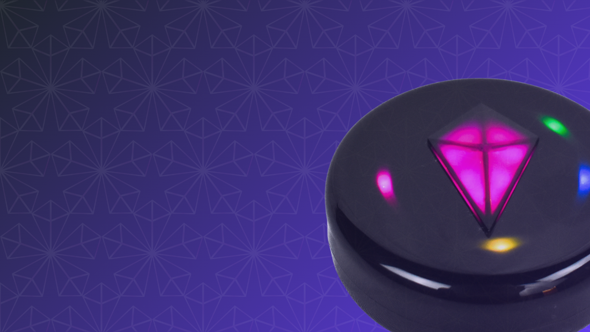 Close-up of a black Totem Compass with its Touch Crystal glowing pink and colored Bond lights around the edge, on a purple patterned background