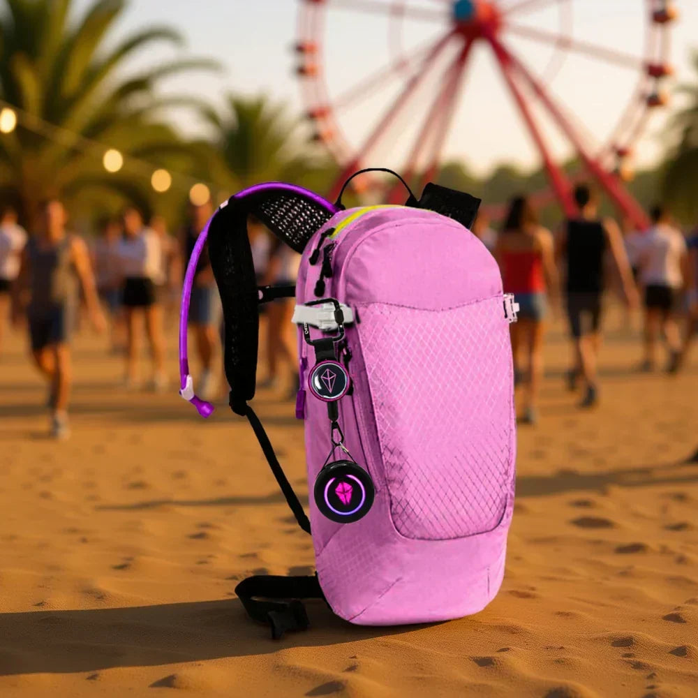 Pink backpack on festival sand with a Totem Compass clipped to its strap on a TotemLoop tether