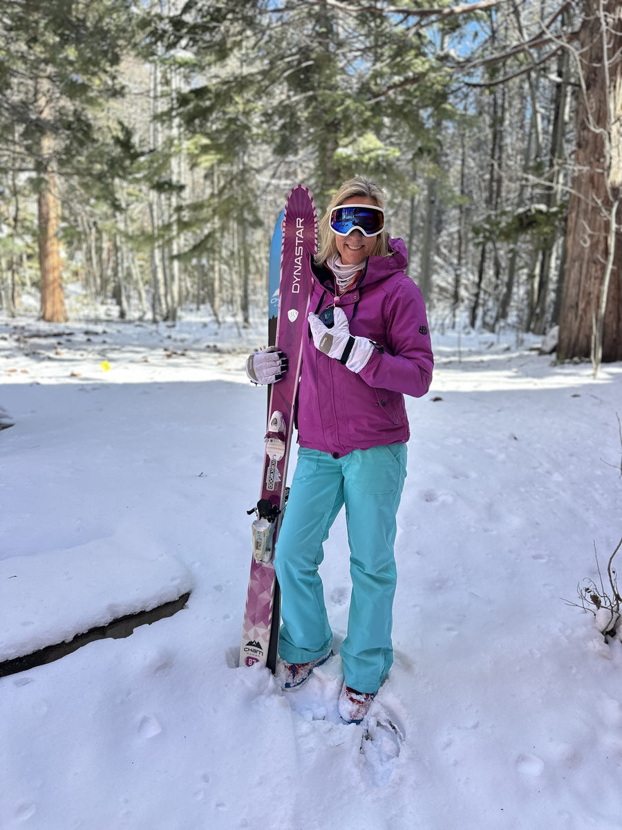 Skier in the snowy woods holding up her Totem Compass